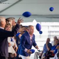 Guests on stage throwing footballs into the crowd at the Jamie Hosford Football Center dedication.